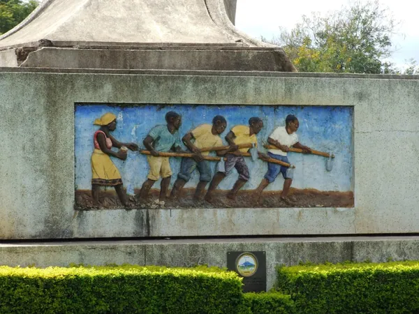 A mural on the base of the Arusha Declaration Monument: people working together.