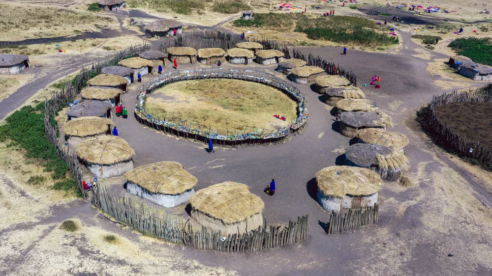 Aerial view of a circular Maasai homestead with thatched houses around a central cattle enclosure