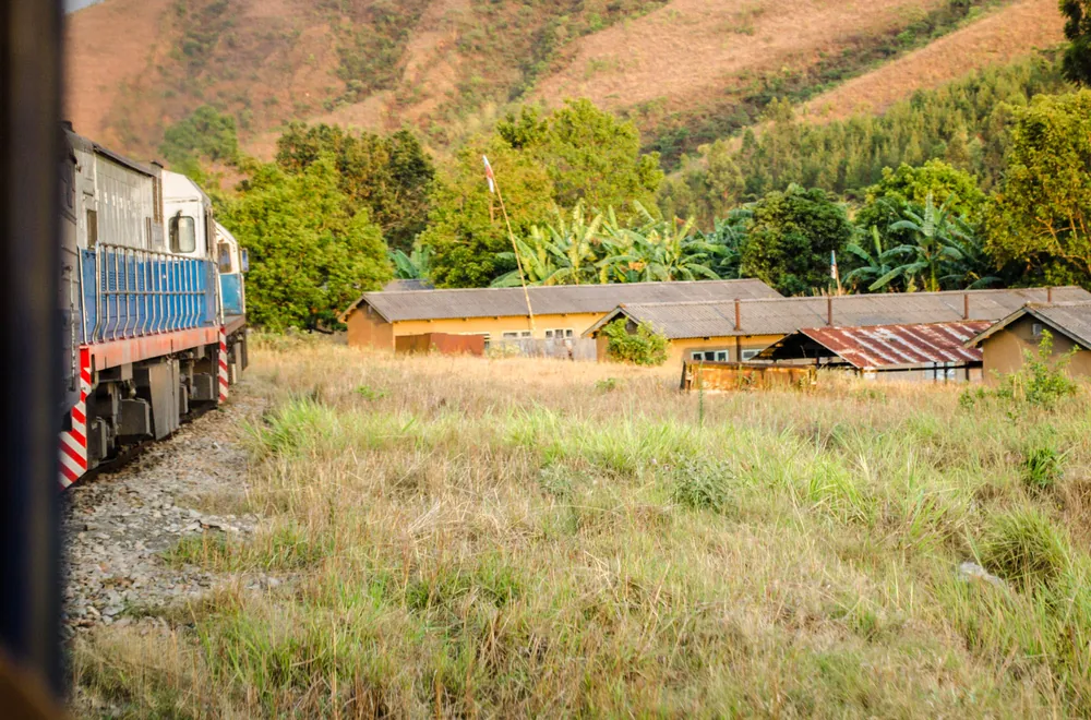 A blue TAZARA passenger locomotive passing a village