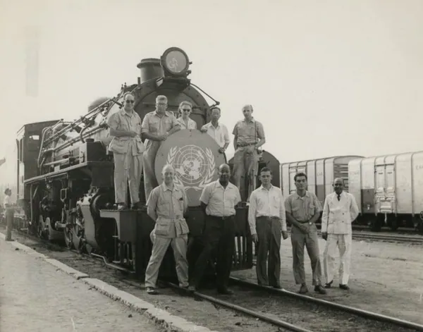 Members of the United Nations Visiting Mission standing in front of a steam locomotive at Tabora, 1957