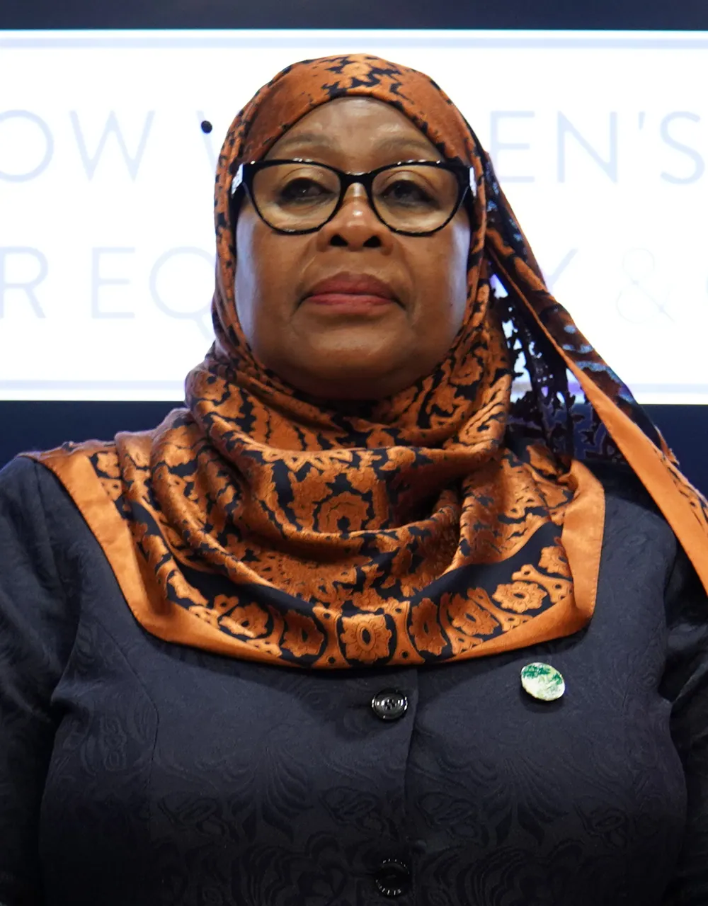 Samia Suluhu Hassan in a patterned headscarf, signing a statement